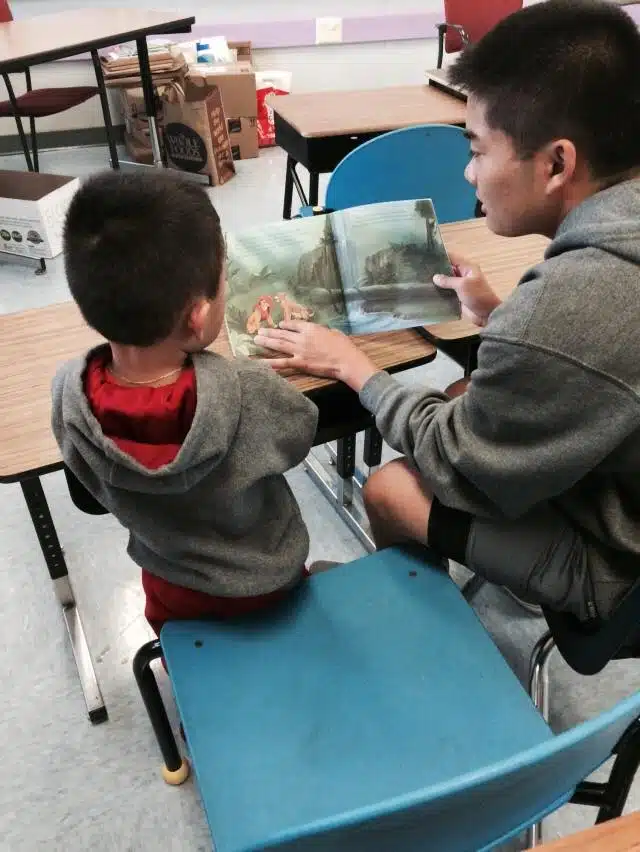 Young man reading to a small boy